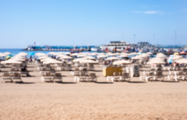 Blurred defocused background of tropical summer beach with beach umbrellas and deck chairs for concept summer vacation Ocean water and horizon over sea