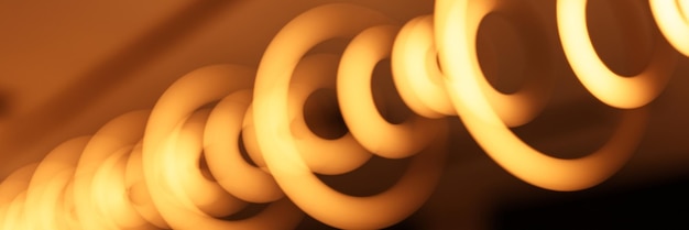 Blurred hanging lamp bulb in the form of rings blur beautiful abstract lighting under the ceiling from modern pendant electricity round lamps chandelier glowing golden yellow dim light inside a room