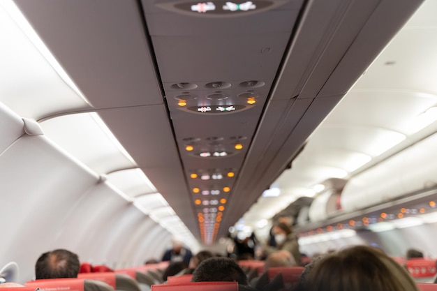 Blurred heads of people sitting on airplane with air ventilation system seatbelt and smoke signs on