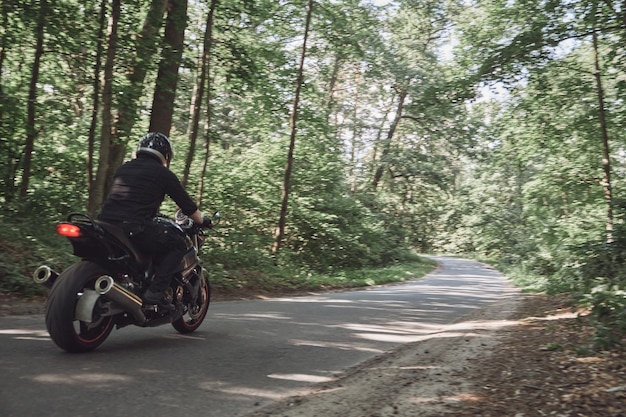 Blurred motion a young man biker in a helmet quickly rides at high speed on a forest road in motion