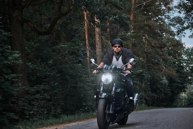 Blurred motion a young man biker in a helmet quickly rides at high speed on a forest road in motion