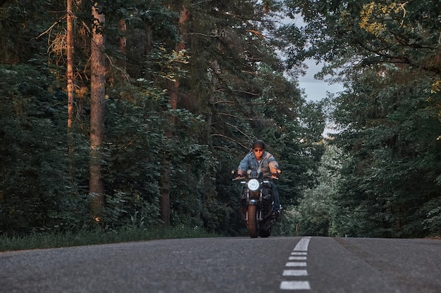 Blurred motion a young man biker in a helmet quickly rides at high speed on a forest road in motion