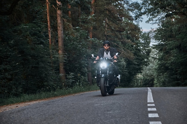 Blurred motion a young man biker in a helmet quickly rides at high speed on a forest road in motion