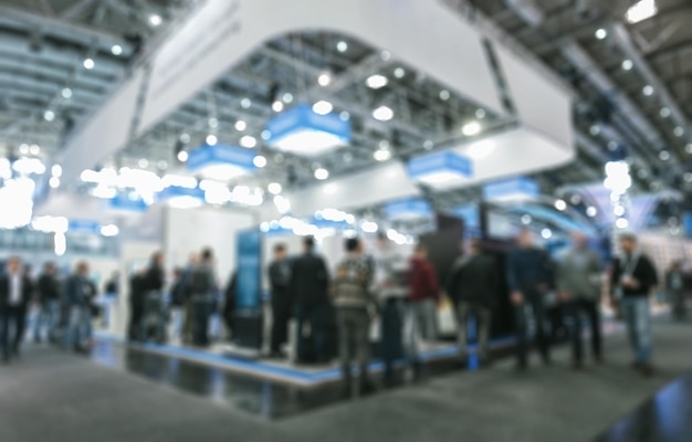 blurred people rushing, standing, walking in a tradeshow hall, generic background with a blur effect applied. ideal for websites and magazines layouts