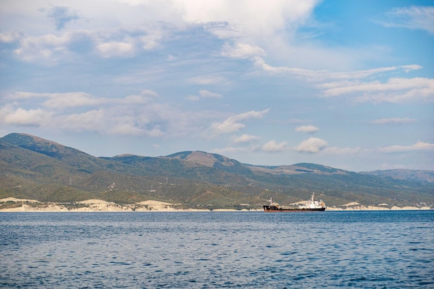 Blurred ship in the black sea against the background of green mountains