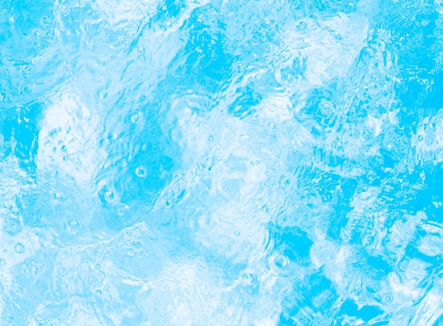 Blurred transparent blue colored clear calm water surface texture with splashes and bubbles Trendy abstract nature background Water waves in sunlight water background