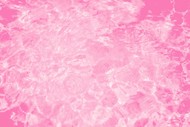 Blurred transparent pink colored clear calm water surface texture with splashes and bubbles Trendy abstract nature background Water waves in sunlight water background