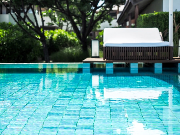 Blurred view of pool with white sunbed in the resort.