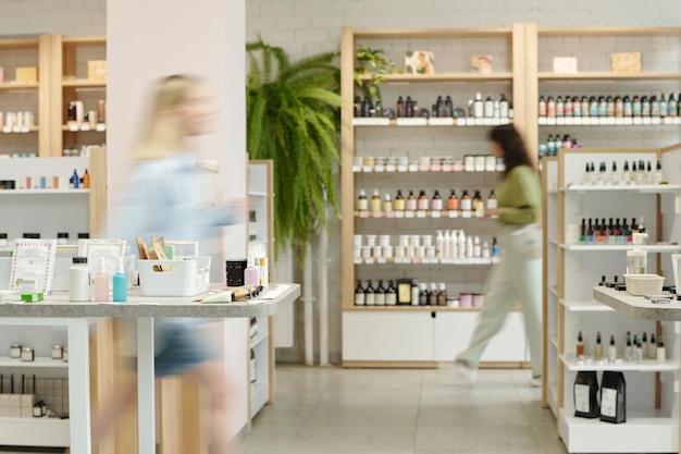 Blurry motion of two young women moving along displays with self care items