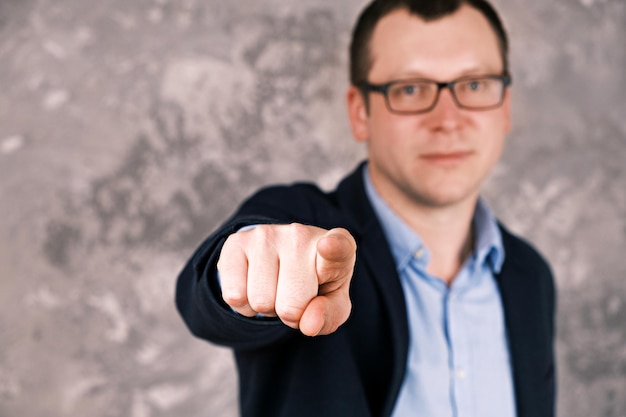 Blurry portrait of a young confident smiling modern businessman in glasses in a suit against the bac