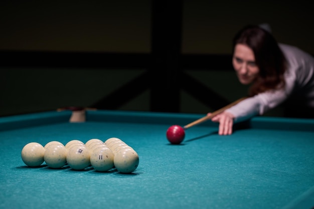 Blurry silhouette of a girl playing billiards in the club