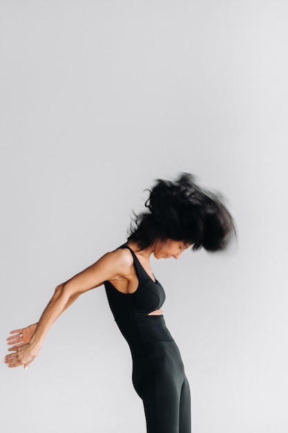 A blurry silhouette of a woman in black sportswear is engaged in dynamic kali meditation in the yoga hall