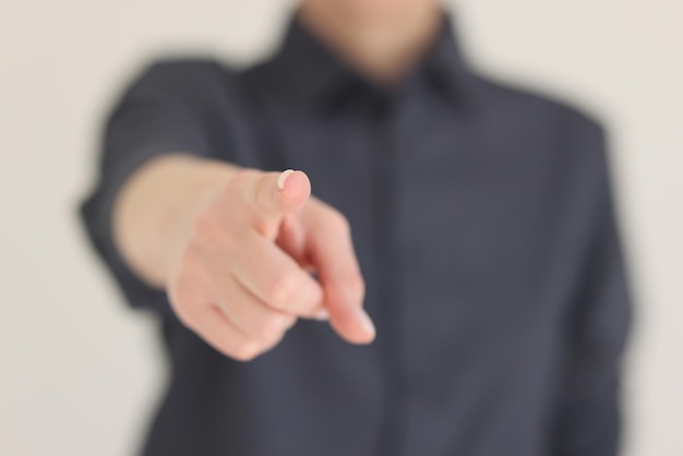 Blurry woman points index finger to camera on beige background female person shows pointing