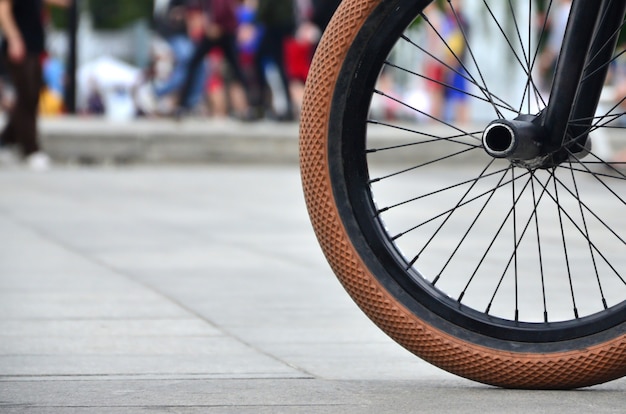 A BMX bike wheel against a blurred street with cycling riders. Extreme Sports Concept