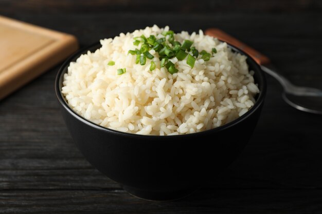 Photo board, bowl of delicious rice and spoon on wooden surface, close up