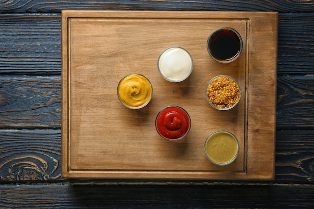 Board with different sauces on wooden background