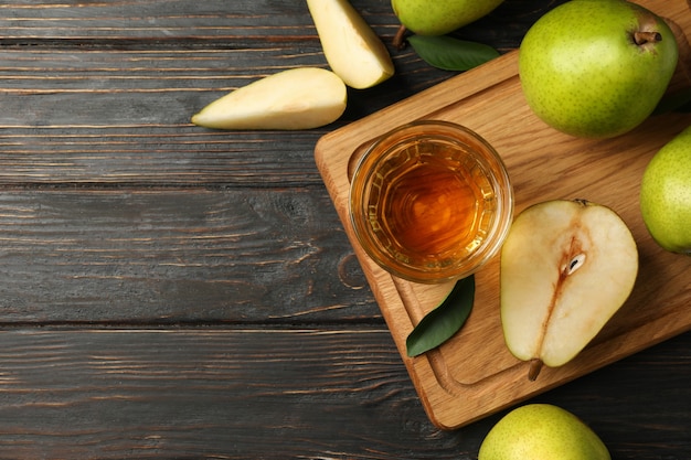 Board with fresh green pears and juice on wooden table