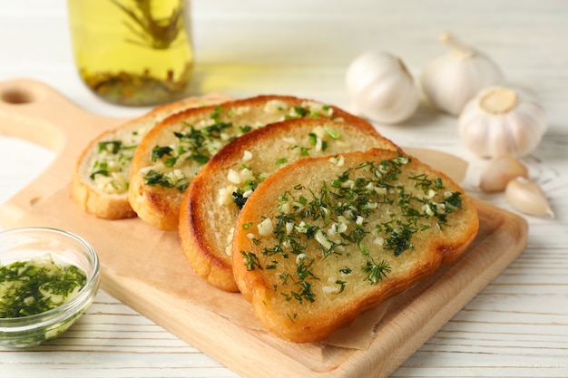 Board with garlic bread on white wooden