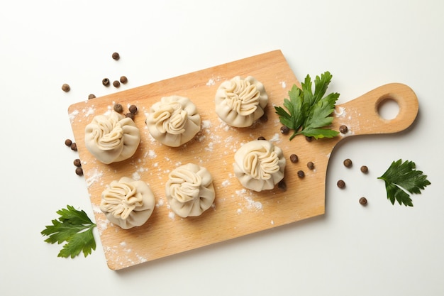 Board with khinkali, spices and flour on white background