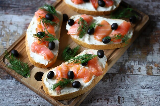 A board with smoked salmon and black olives on it