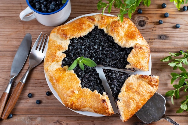 Board with tasty blueberry galette on table