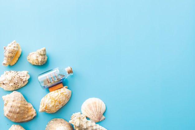 a boat in a bottle and seashells on a blue background