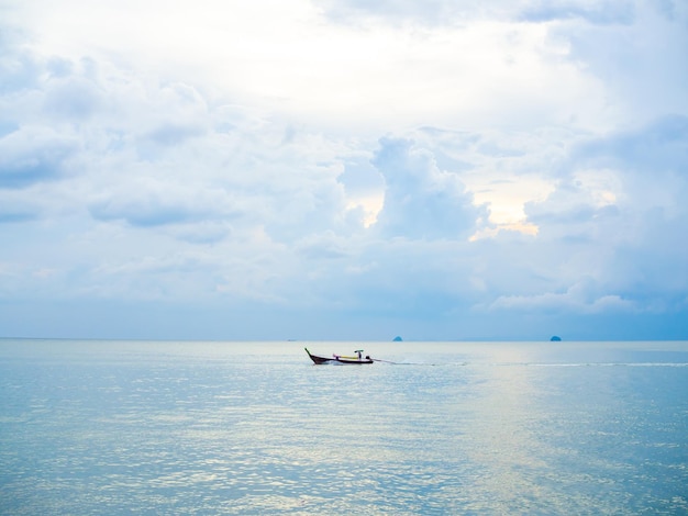 Boat driver on traditional long tail boat in the sea with cloud and sky background on sunset in Thailand minimalist style