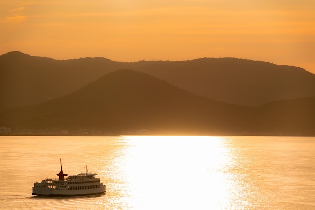 Boat ferry is travel along Takamatsu islands in Japan, with golden sunset reflection sky for Vacation and Japan travel concept