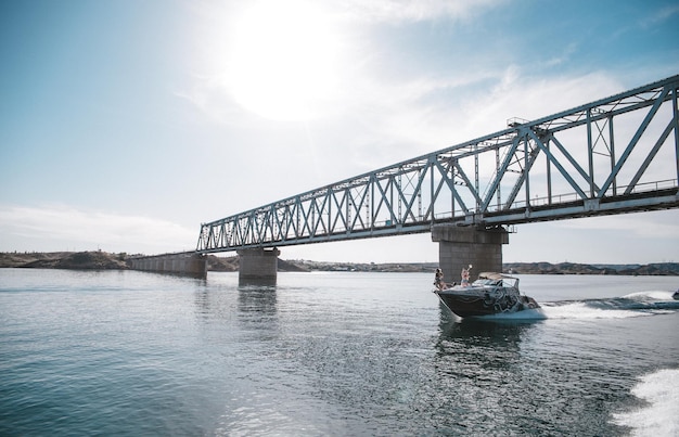 Boat floats on water under bridge on clear summer day