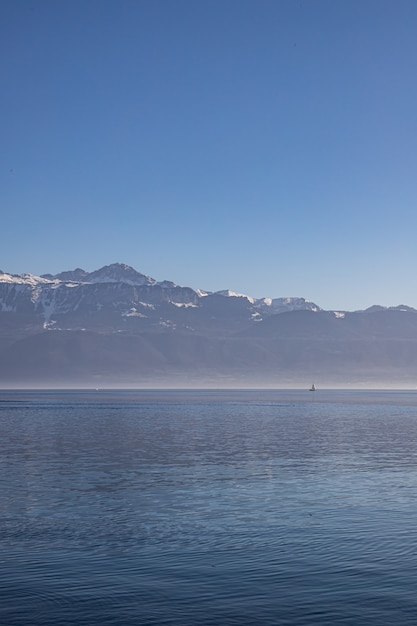 Boat on hazy, misty Lake Geneva and the Alps seen from Lausanne, Switzerland