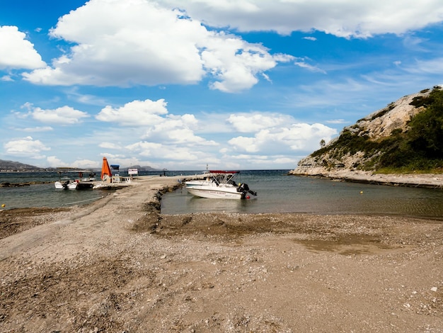 A boat is docked in the water near a hill.