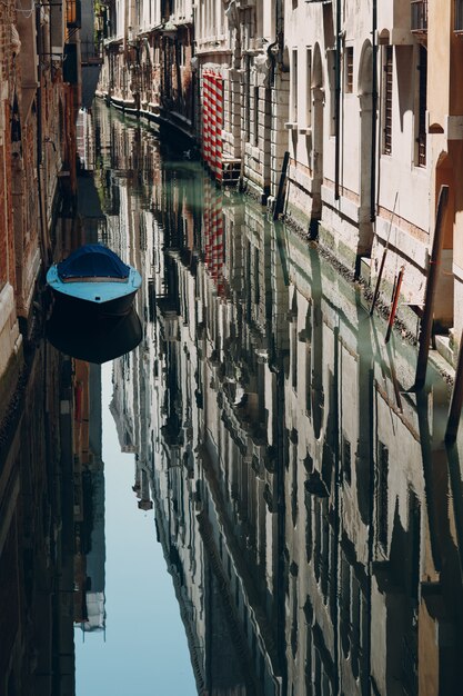 The boat is reflected in the perfectly smooth surface of the canal in Venice