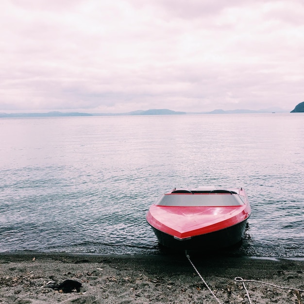 Boat moored at beach against sky