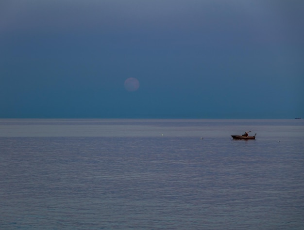 A boat and a rising moon in a Mediterranean beach of Ionian Sea Bova Marina Calabria Italy