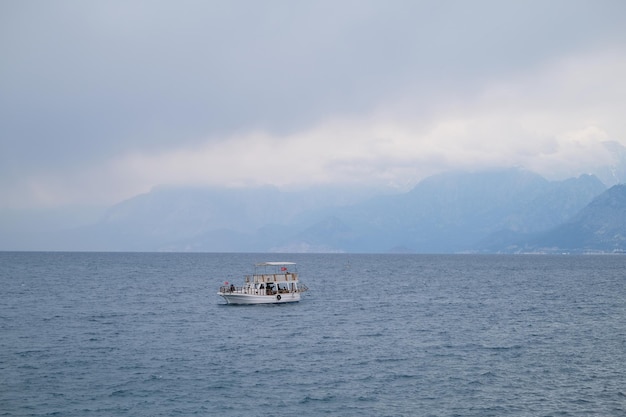 Boat with tourists in the sea against the backdrop of mountains in the fog