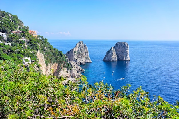 Boats at Faraglioni cliffs and Tyrrhenian Sea in Capri Island, Italy