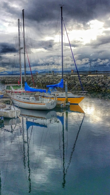 Photo boats in harbor against cloudy sky