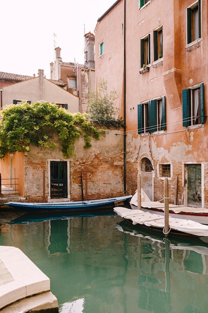 Boats moored at the walls of a building in a canal in venice italy classic venetian street views