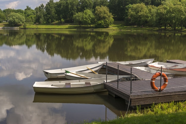 Boats at the pier on a small river. The lifeline hangs on the dock