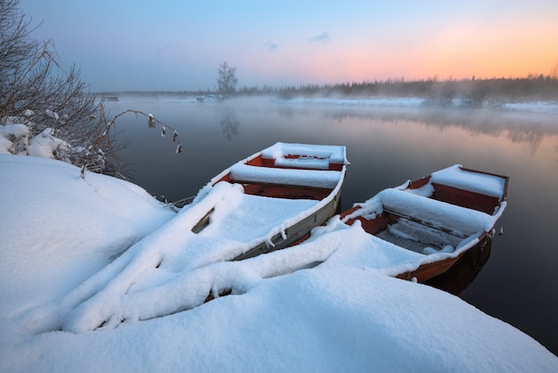 Boats in snow at the river in the winter