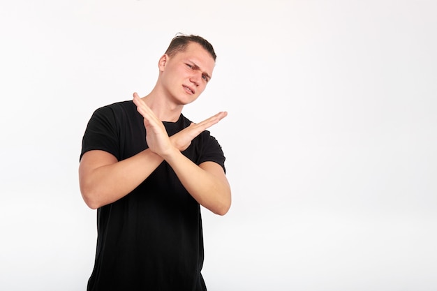 Body language. Young unhappy man crossed his arms in front of him and showing a gesture of denial or stop