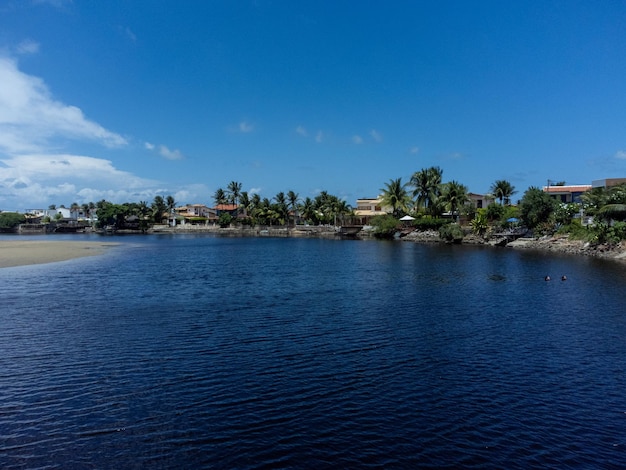 a body of water with a beach and houses in the background