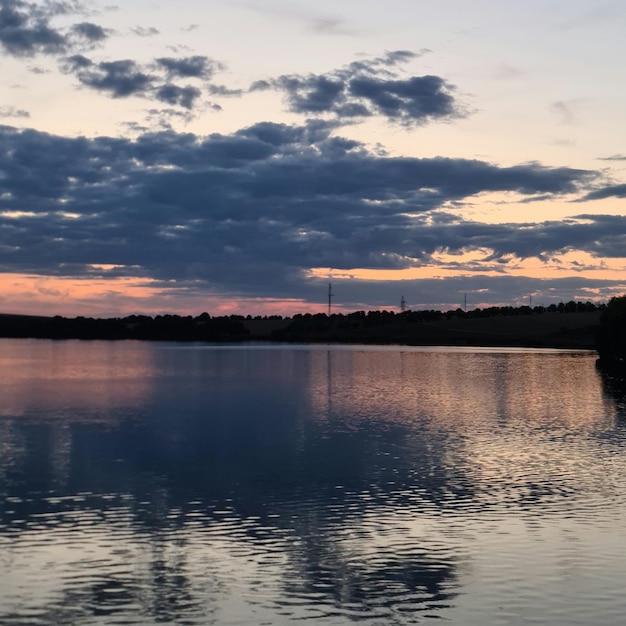 A body of water with trees and clouds in the sky