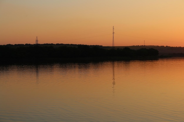 A body of water with trees and power lines in the background