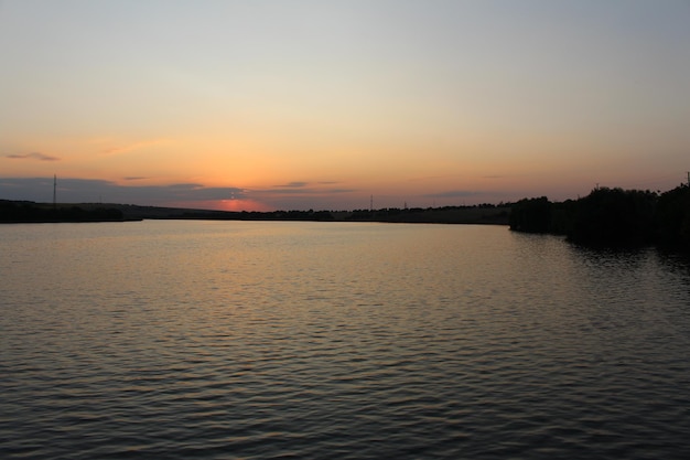 A body of water with trees and a sunset