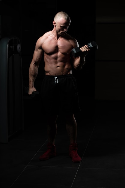 Bodybuilder Exercising Biceps With Dumbbells