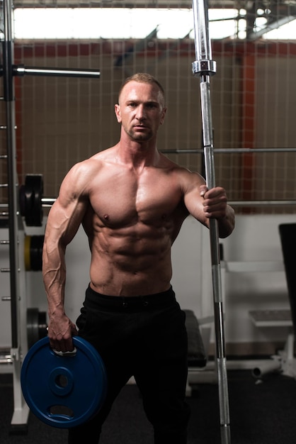 Bodybuilder Flexing Muscles With Barbell and Weights