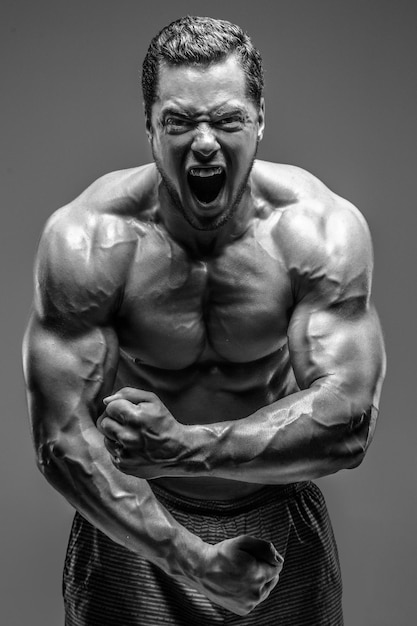 Bodybuilder posing in studio. Isolated on grey background.