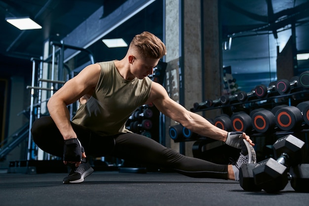 Bodybuilder stretching upper body in gym.