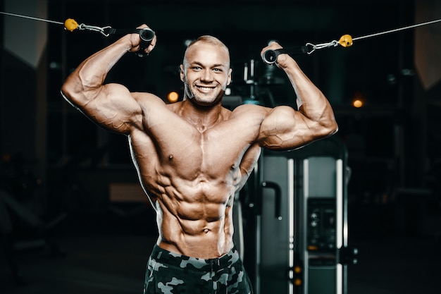 Bodybuilder strong man pumping up biceps muscles